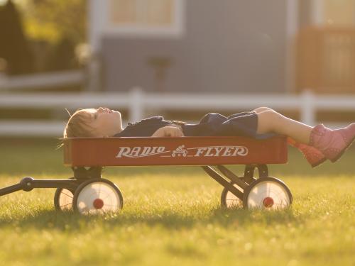 Horizontal photo of a child in a red wagon. 