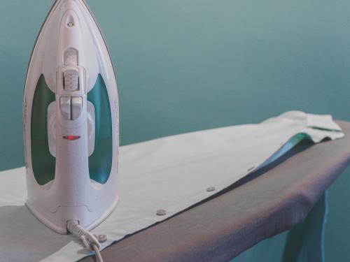 Vertical photo of an iron on an ironing board and T-shirt.