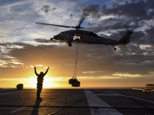 Horizontal photo of a medvac helicopter about to land with the sun in the background.