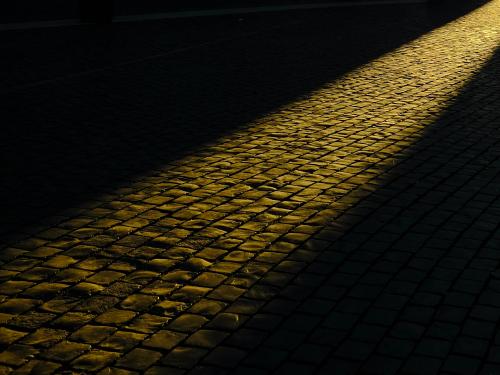 Cobblestones at night with beam of light running across them.