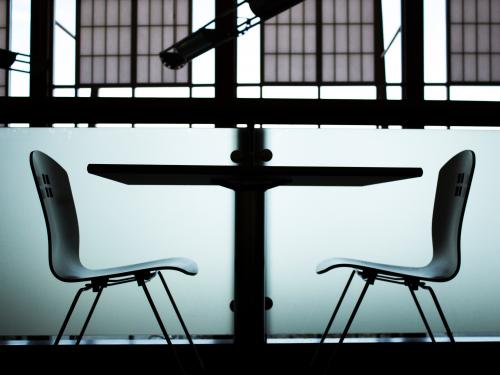 Horizontal photo of two chairs symmetrically facing a table. 